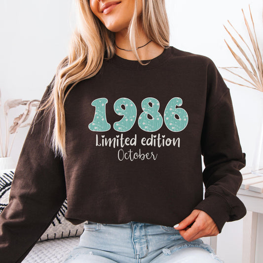 White crewneck sweatshirt featuring floral patterned 1986 numbers with special edition June text, feminine retro birthday design for a 40th milestone celebration.