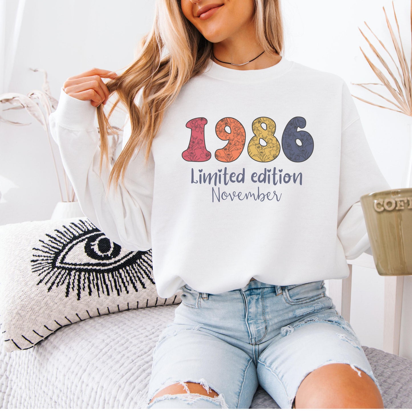 White crewneck sweatshirt featuring colorful floral 1986 numbers with limited edition November text, retro inspired 40th birthday design for women.