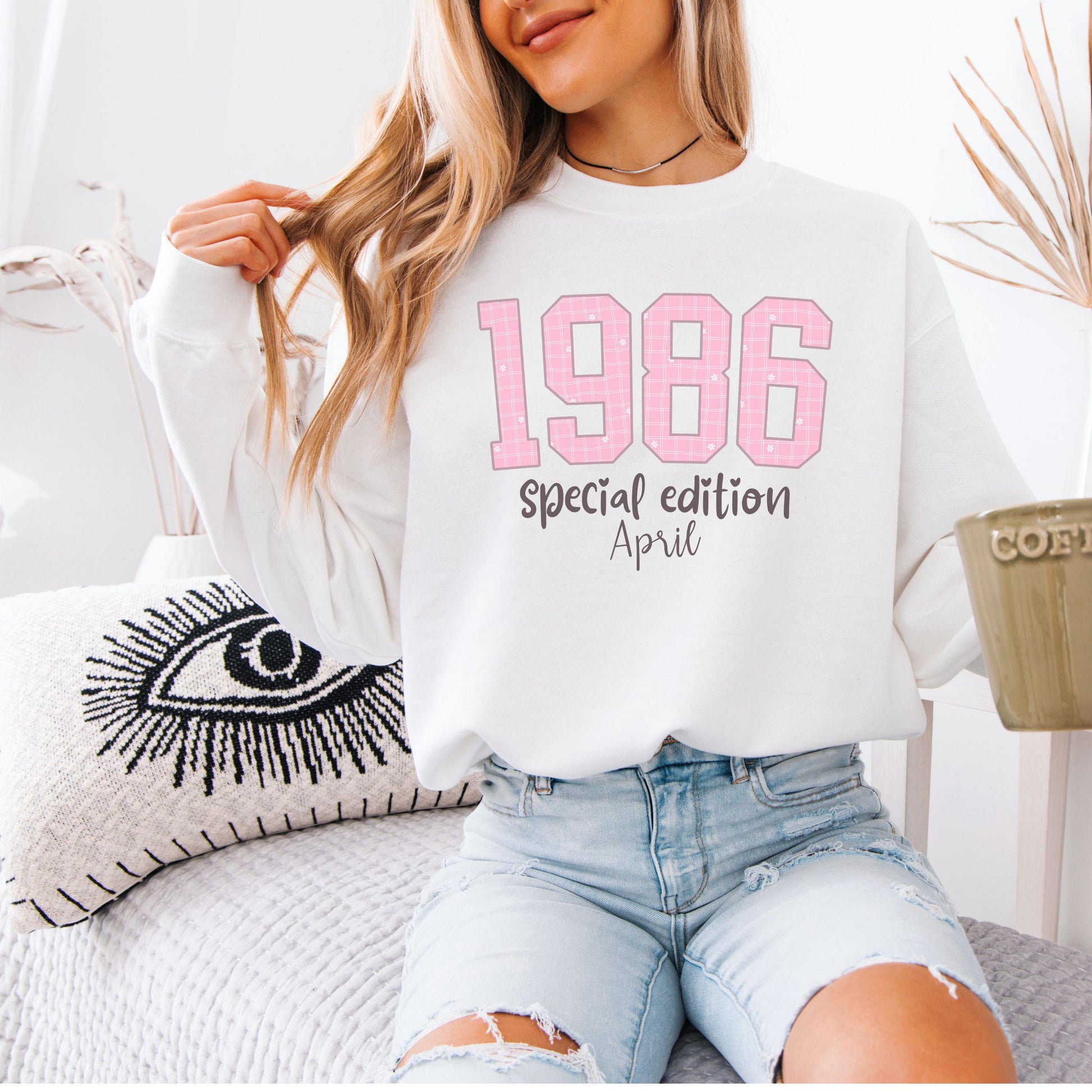 White crewneck sweatshirt featuring pink patterned 1986 numbers with special edition April text, feminine retro design for a 40th birthday celebration.