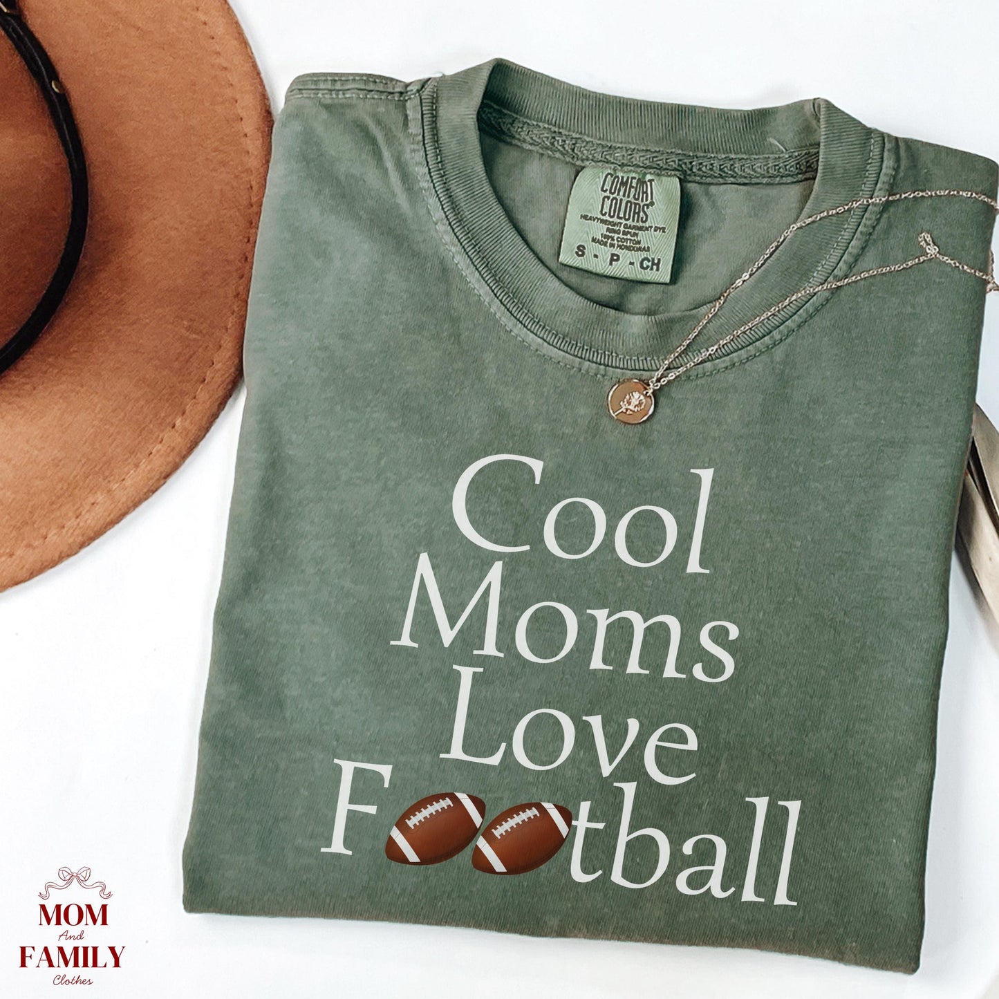folded brown comfort colors® shirt with white text "Cool Moms Love Football" and football emoji accents, ideal for sporty moms or game day