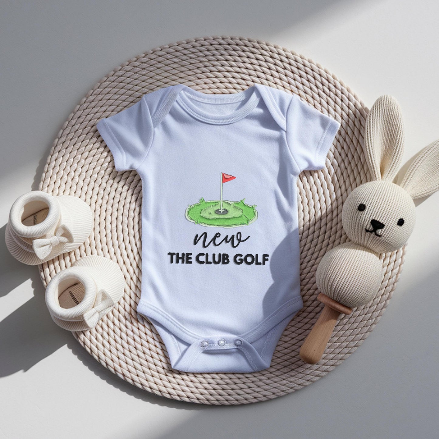 White baby bodysuit with embroidered golf green and flag design reading new to the club golf, newborn pregnancy announcement outfit for golf loving dad.