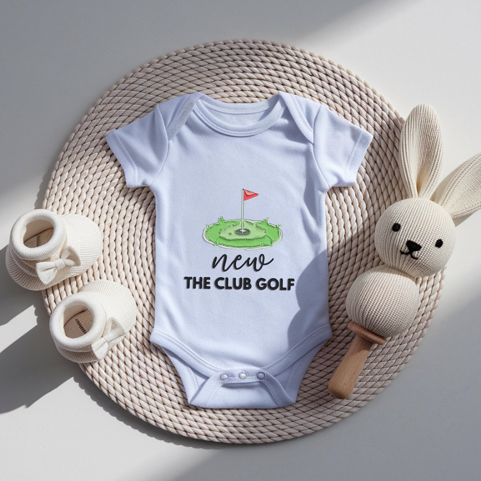 White baby bodysuit with embroidered golf green and flag design reading new to the club golf, newborn pregnancy announcement outfit for golf loving dad.
