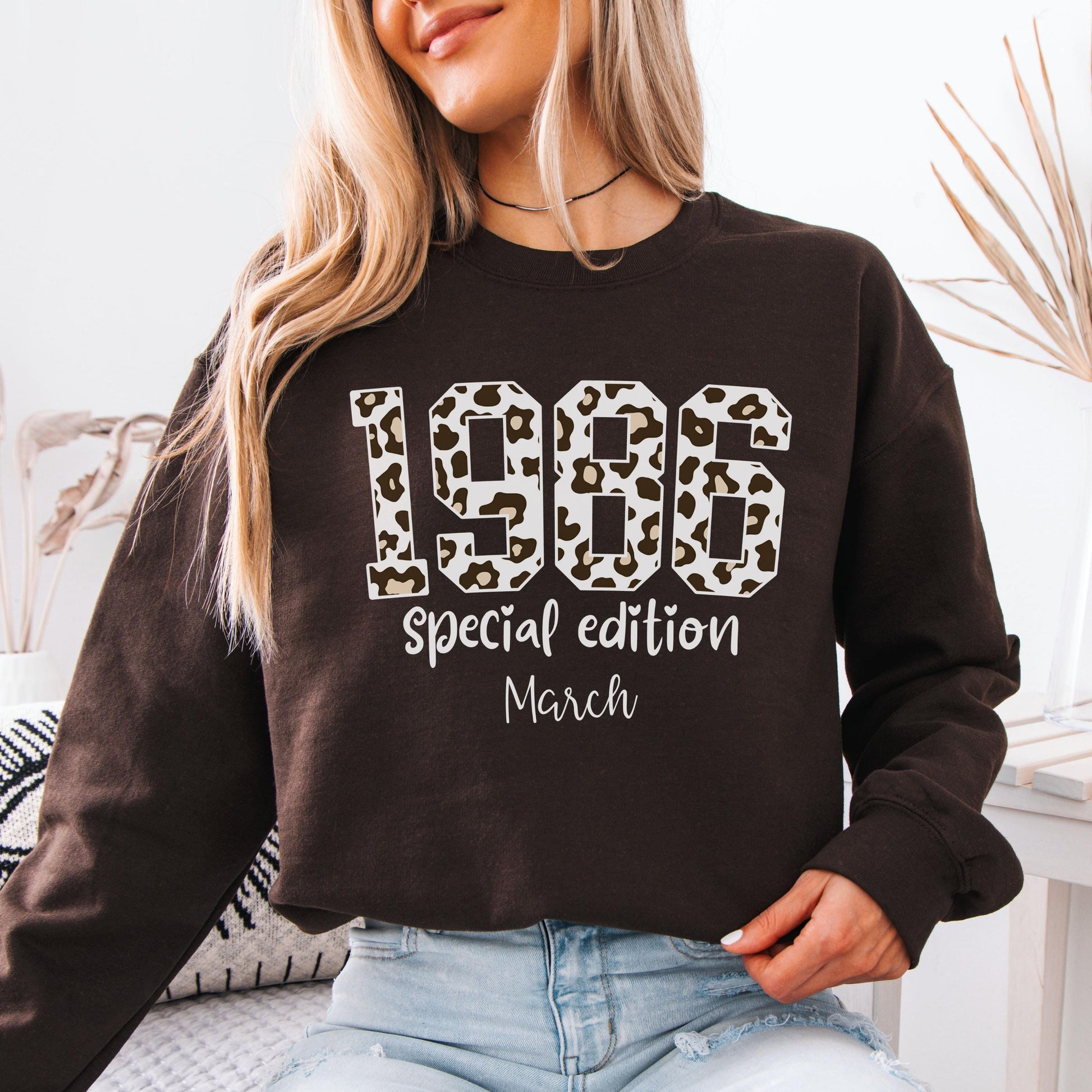 Dark brown crewneck sweatshirt featuring leopard print 1986 numbers with special edition March text, trendy retro design for a 40th birthday celebration.