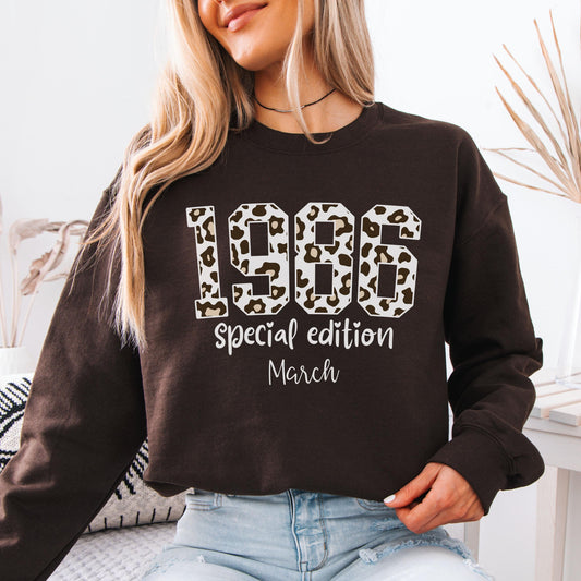 Dark brown crewneck sweatshirt featuring leopard print 1986 numbers with special edition March text, trendy retro design for a 40th birthday celebration.